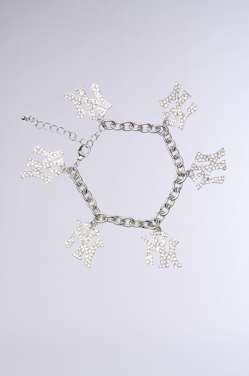The LOVE YOU NY BRACELET is a silver chain bracelet, featuring six "Y" and "N" charms adorned with sparkling rhinestones. Its NYC-inspired design is beautifully presented on a light grey background, accentuating its chain link construction.
