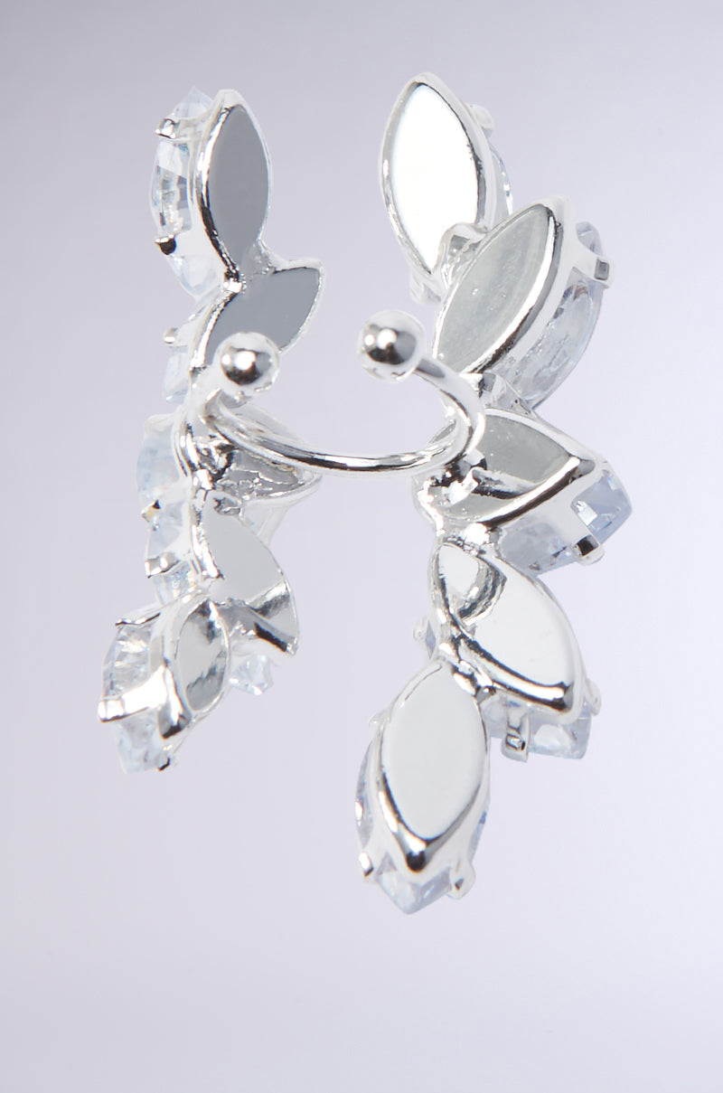 Close-up of a CHARMER FAUX LIP RING crafted in silver, featuring leaf-shaped embellishments with a curved metallic base. The piece is adorned with reflective surfaces and clear teardrop-shaped gemstones, set against a light gray background. 4
