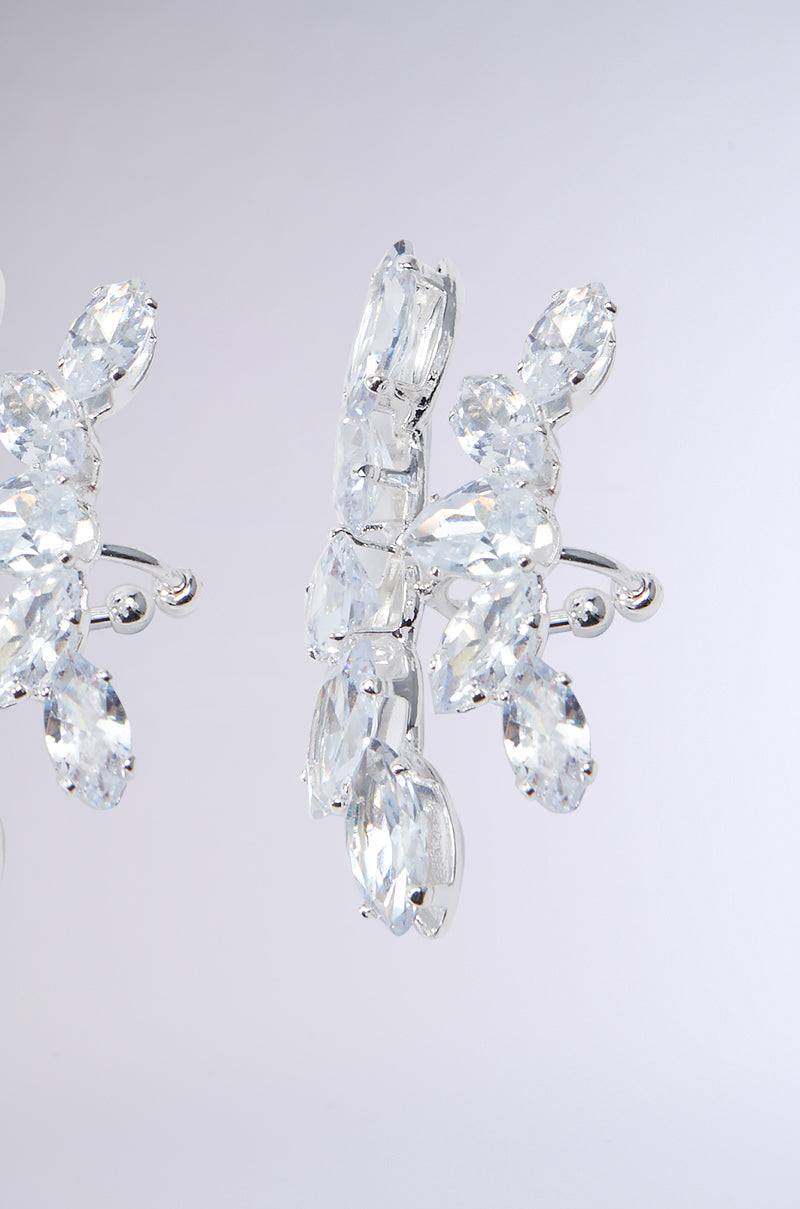 Close-up of the exquisite CHARMER FAUX LIP RING, showcasing a silver-hued design adorned with clusters of clear, faceted gemstones arranged in a delicate floral pattern on its metallic base. The softly blurred background enhances the intricate craftsmanship and dazzling sparkle of this exceptional piece. 5