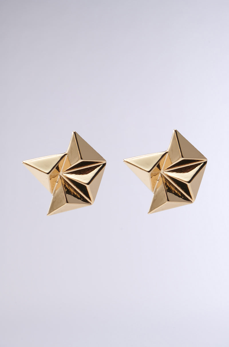 A pair of TRIFECTA EARRING from AKIRA Label with a geometric silhouette on a light gray background. These star-shaped faux gold accessories feature a shiny, polished finish and an intricate 3D design.