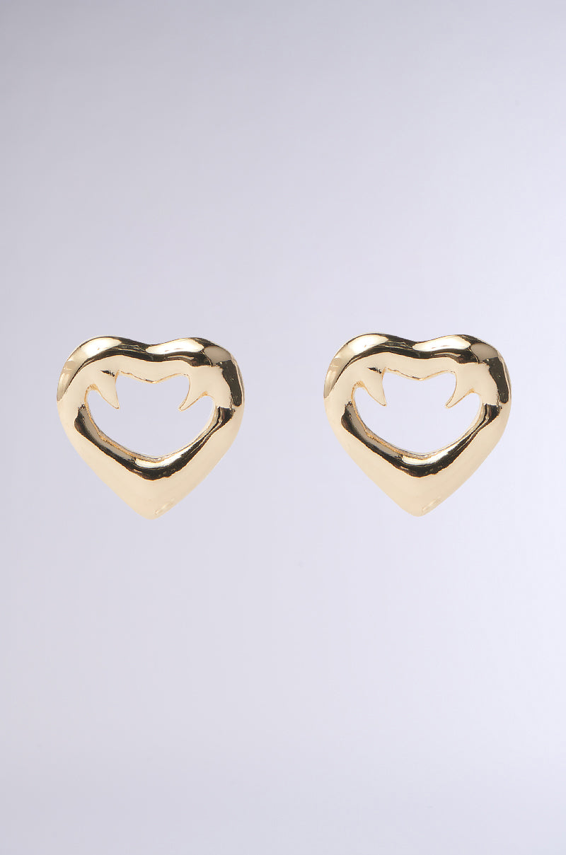 Introducing the LOVE KILLS GOLD EARRING by AKIRA Label, featuring exquisite heart-shaped gold earrings with an abstract cutout design at the center, elegantly displayed against a light gray backdrop.