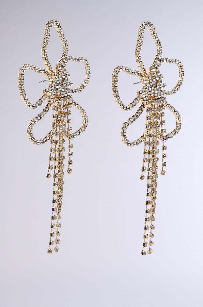 The IN THE GARDEN EARRING features flower-shaped dangle earrings with loops, adorned with rhinestone-encrusted gemstones and cascading strands of smaller stones on a plain background.
