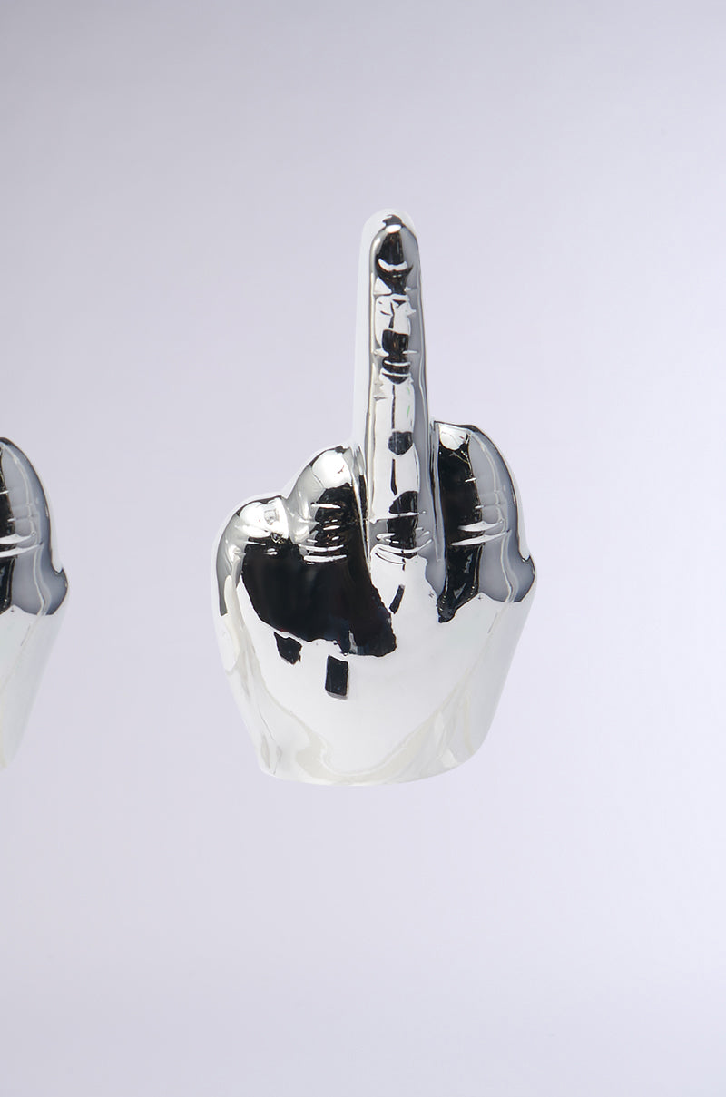 Introducing the MY MOOD EARRING: A striking silver earring crafted in a bold hand shape, elegantly showcasing the middle finger gesture. Its highly polished surface reflects light and surroundings, transforming it into a captivating statement piece against any plain white backdrop. 3