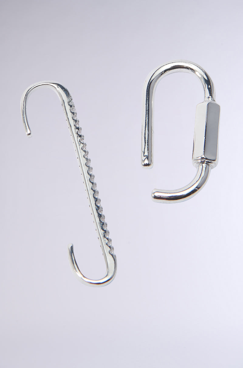 Close-up of two silver metal objects on a light background from the EPIC VIEWS EAR CUFF SET. The left item is a serrated hook similar to a carabiner ear cuff, while the right features a smooth hook with a cylindrical attachment. Both exhibit an elegant, shiny finish. 1