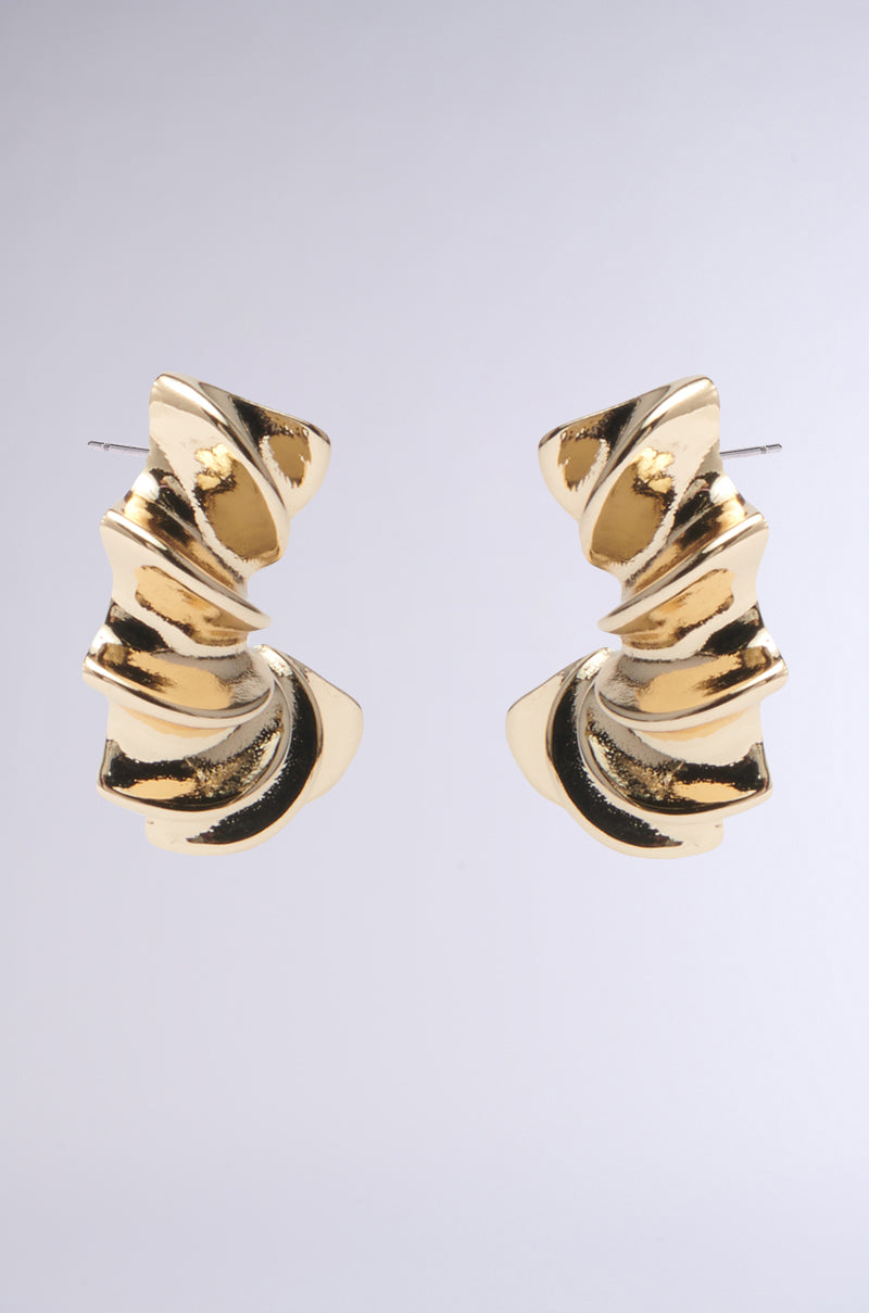 The BELLA NOCHE GOLD EARRING features gold-tone spiral hoops with a twisted, abstract design that adds sculptural flair against a plain gray background. 2