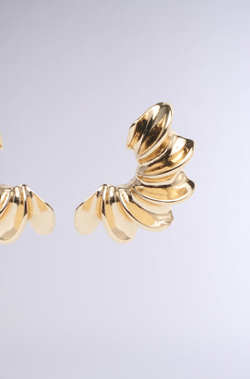The BELLA NOCHE GOLD EARRING boasts an abstract, shell-inspired design with a polished finish. Set against a light gray background, the earrings feature layered, curved segments resembling fan shells for a unique chunky look. 3