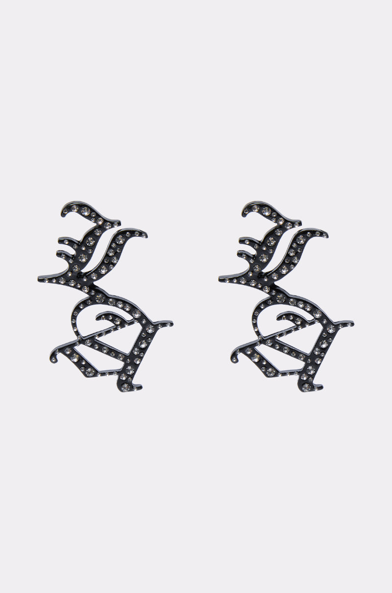 The WRITE ABOUT ME EARRINGS are black metal earrings shaped like abstract birds, adorned with small sparkling clear rhinestones, shown against a plain white background. 0