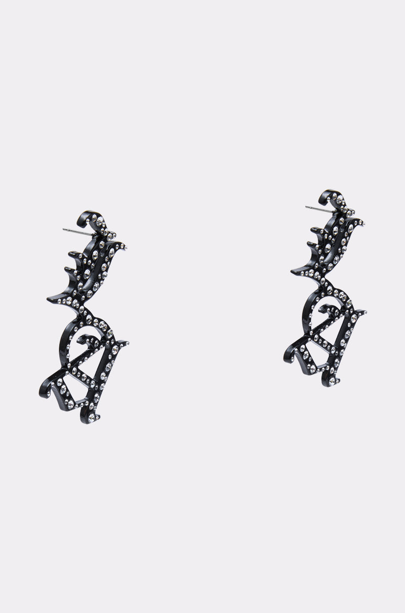 The WRITE ABOUT ME EARRINGS are a striking pair of black rhinestone earrings featuring intricate abstract designs and sparkling stones, inspired by bold LA earring styles and displayed on a plain light background. 2