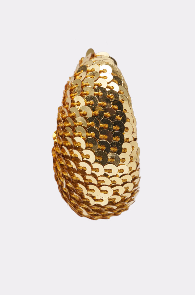 The GIMME THE GLITTER HOOP EARRING features a teardrop shape with overlapping shiny gold sequins, creating a textured, disco-glam look that pops against a simple light background. 4