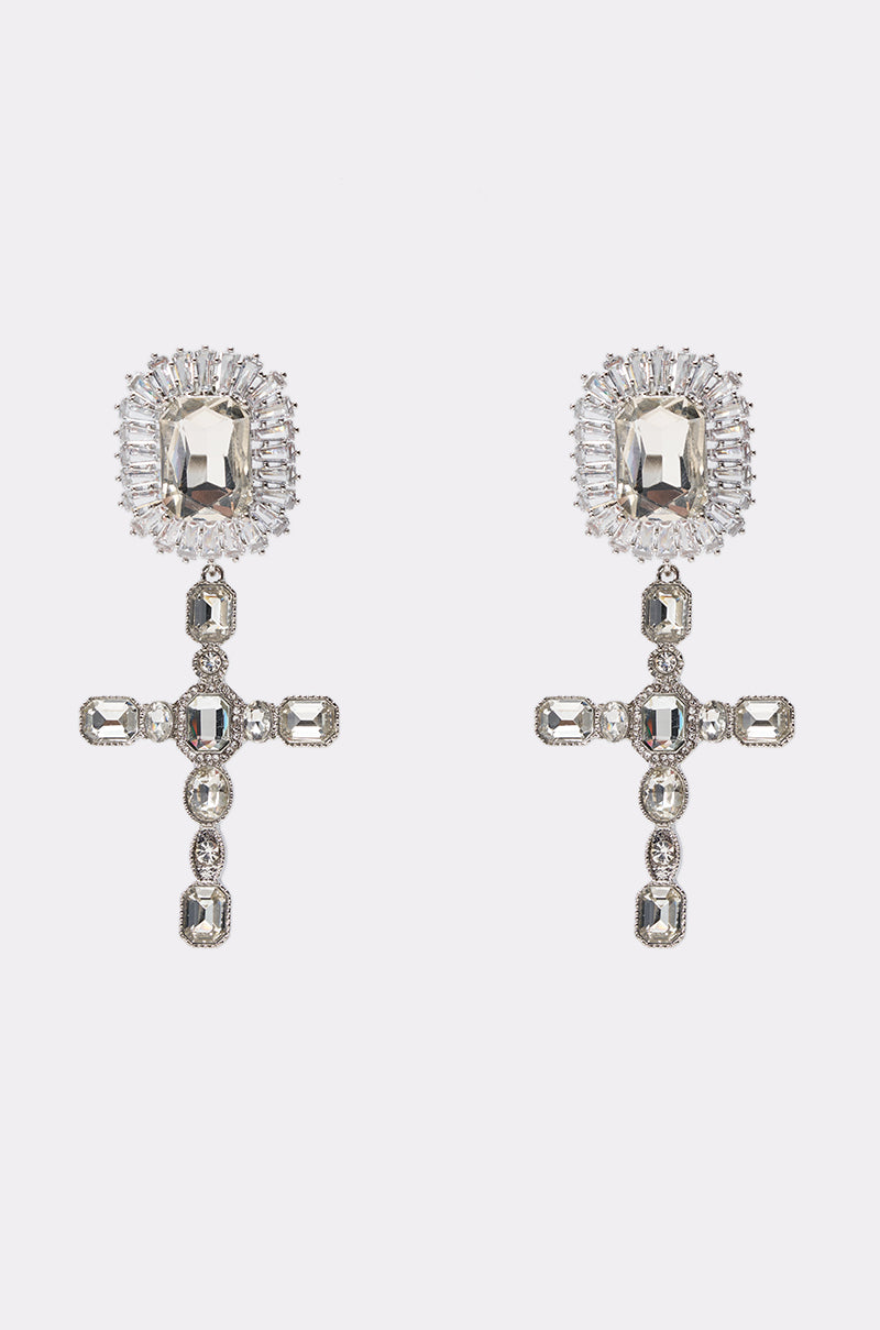 The CROSS YA HEART EARRING features silver cross-shaped drops with large rectangular gems at the top, surrounded by sparkling stones and geometric accents forming an elegant cross below. 0