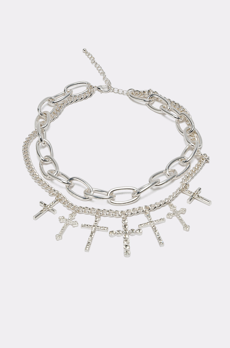 The CROSS MY HEART SILVER NECKLACE features chunky and thin layered silver chains, adorned with multiple small cross pendants and sparkling rhinestones, displayed on a plain light background. 4