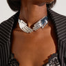 Close-up of a person wearing the STAY IN TOUCH CHOKER NECKLACE, a real statement piece featuring two sculpted hands meeting at the front. They are dressed in a pinstripe blazer and a lace-trimmed top, accentuating the choker necklace and upper part of their outfit.