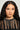 A person with long, wavy black hair wears a sheer black top adorned with the RUNNING IN CIRCLES NECKLACE, featuring o-ring hardware. The neutral background accentuates their poised expression and the bold statement piece.