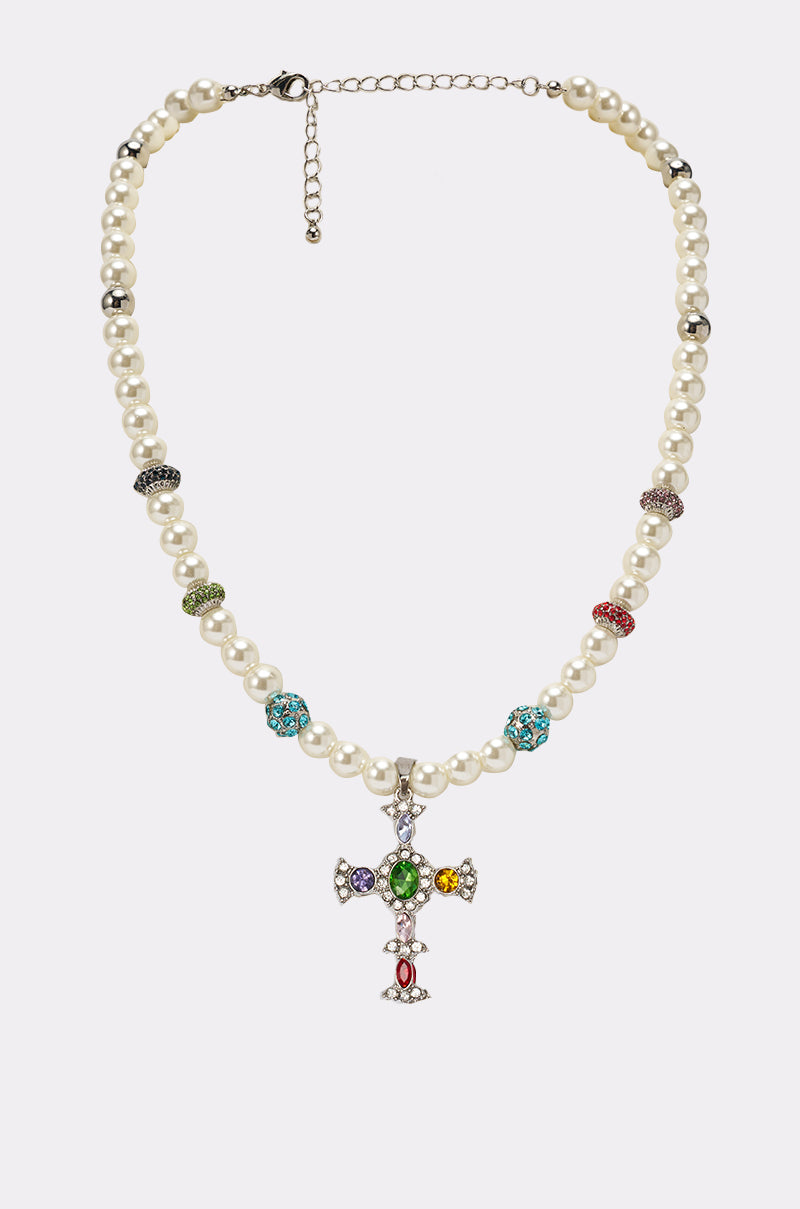 The CANDY CROSS NECKLACE is a faux pearl necklace with colorful gemstone spacers and a jeweled cross pendant adorned with multicolored gems, shown against a plain white background. 0