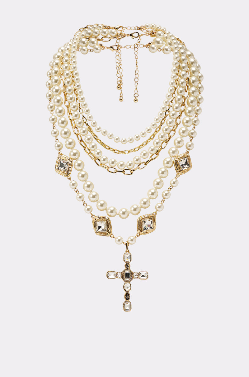 The ITALIAN LOVE NECKLACE SET features a layered faux pearl design with multiple strands, square crystal accents, and a crystal cross pendant, shown against a plain light background. 0