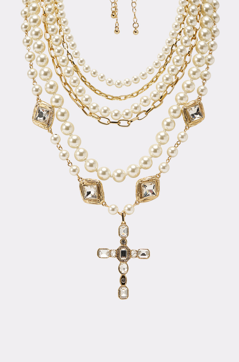The ITALIAN LOVE NECKLACE SET showcases gold-toned chains, faux pearls, square jeweled accents, and a large crystal cross pendant, all displayed against a light background. 3