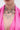 A person wears the IN MY CITY NECKLACE, a layered chain with rhinestone "M" pendants, paired with a sparkling pink top, shown from shoulders to chin.