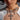 A woman wears a sheer white top and the FOREVER PROTECTED NECKLACE—a bold silver-tone piece with three rhinestone cross pendants. Her striking makeup and serious expression highlight her standout statement jewelry.