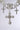 A close-up of the FOREVER PROTECTED NECKLACE, a silver-tone filigree piece with sparkling rhinestone cross pendants and floral accents, all adorned with clear gemstones, set against a plain light background.