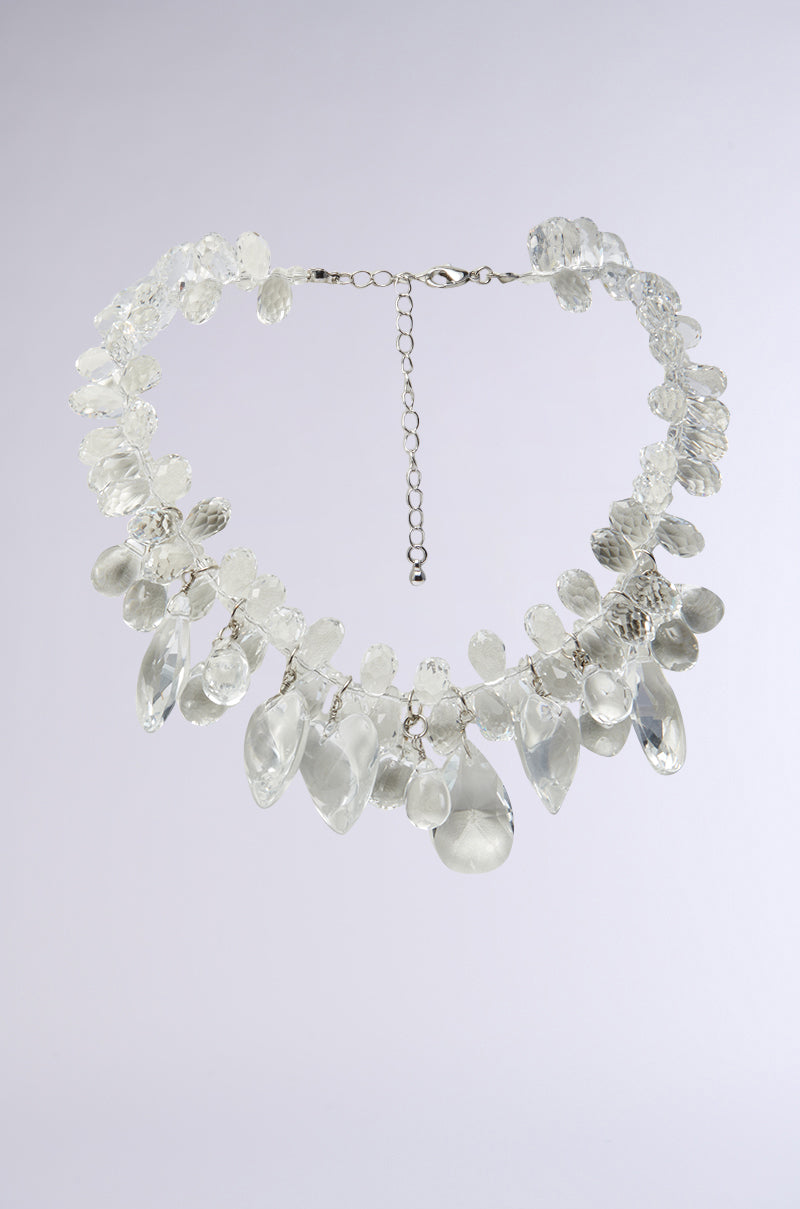 The CLEAR TO ME NECKLACE features large, clear teardrop and oval beads on an adjustable silver chain, making a stunning statement piece shown on a light gray background. 0