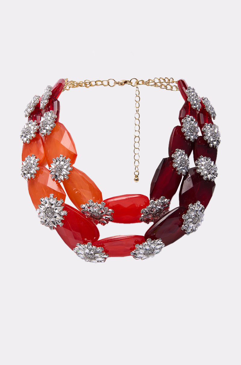 The ESTABLISHED NECKLACE features large red and orange faceted beads, accented by clusters of sparkling silver rhinestones, and finished with a gold adjustable chain clasp. 0