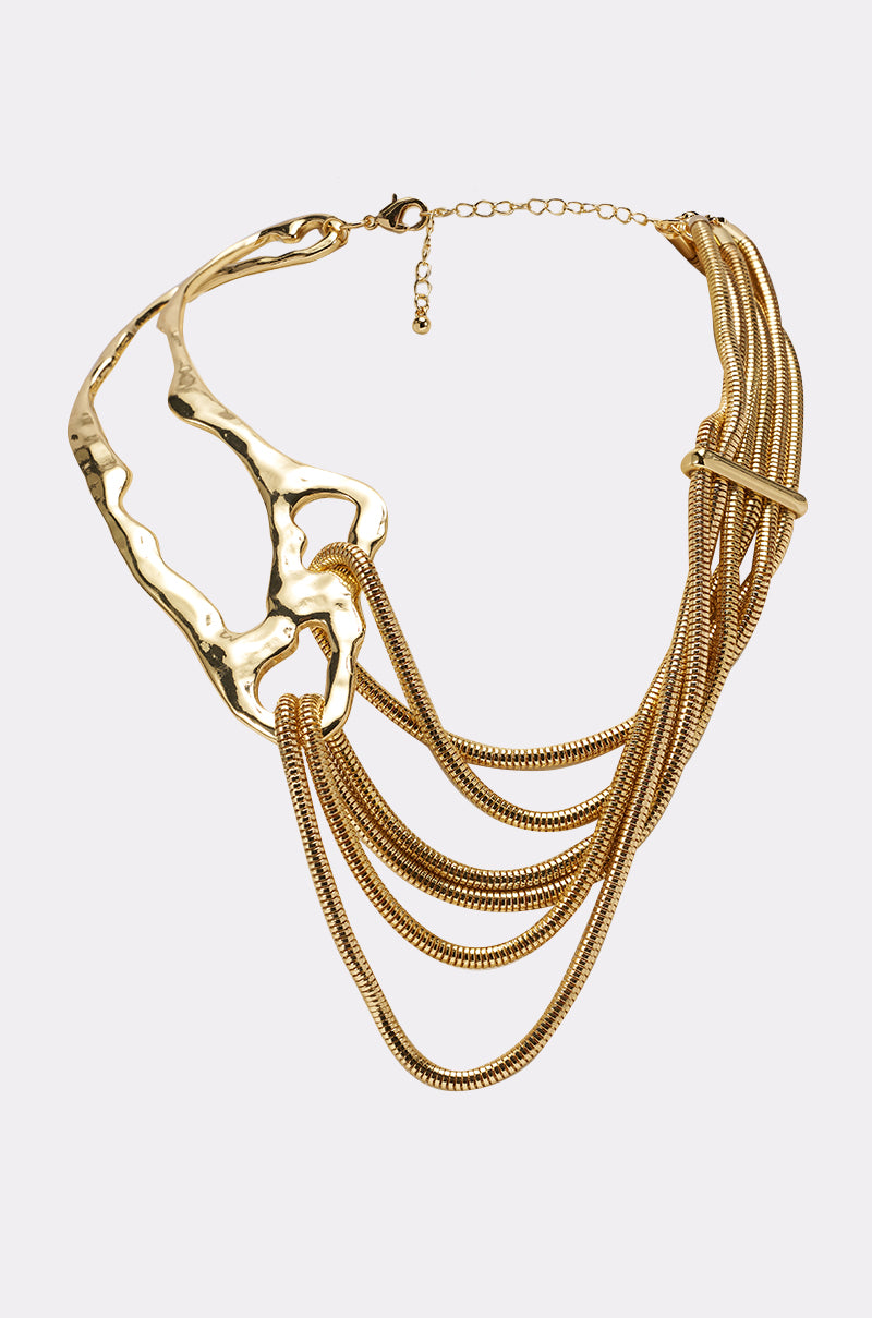The SO DECO NECKLACE is a gold statement piece with an abstract sculpted metal section on one side and layered snake chains on the other, finished with a lobster clasp and an adjustable chain. 0