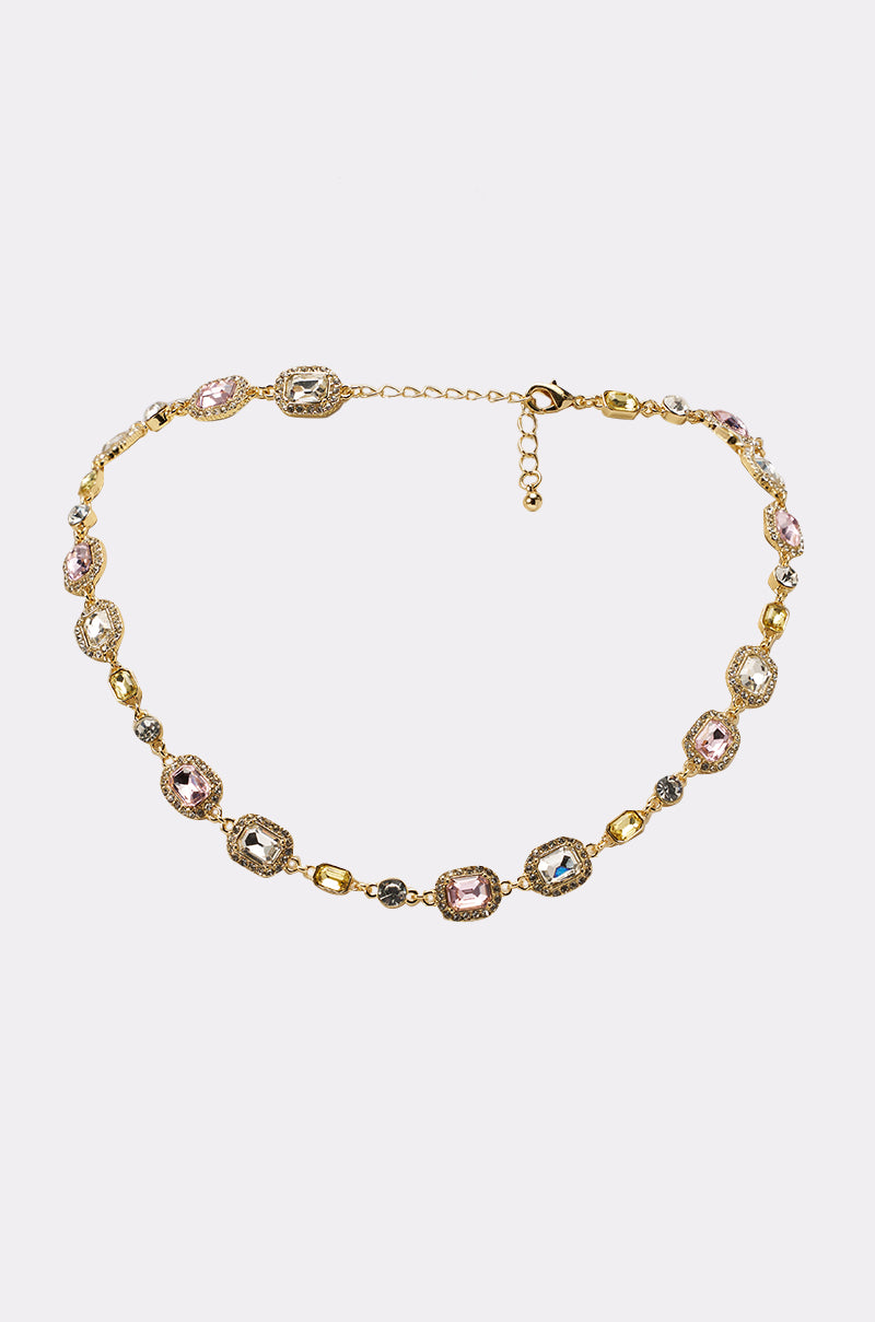 The WITH THE VIBES NECKLACE features a gold chain with alternating oval links and multicolored gemstones in pink, blue, and clear, set in decorative frames—an elegant piece that elevates any formal look with its adjustable clasp closure. 0