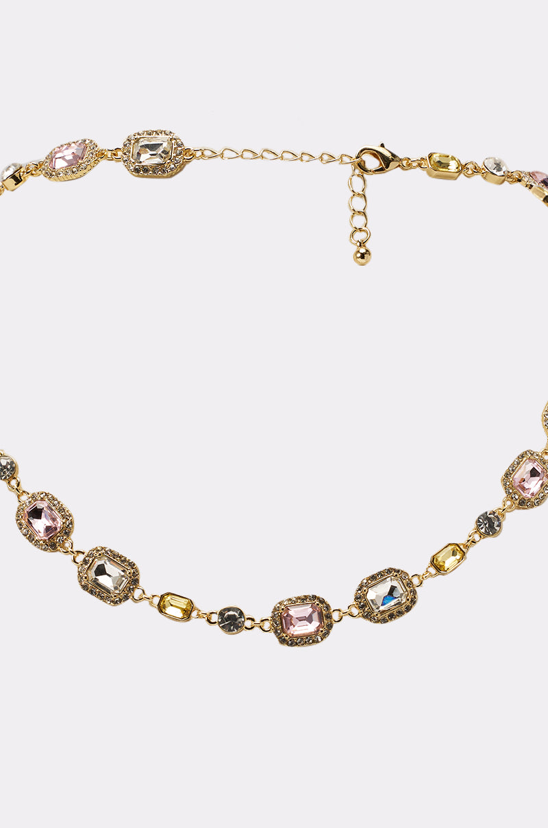 The WITH THE VIBES NECKLACE features a gold-tone chain with rectangular pastel gemstones in pink, yellow, and gray set in ornate bezels, shown against a plain white background. 2