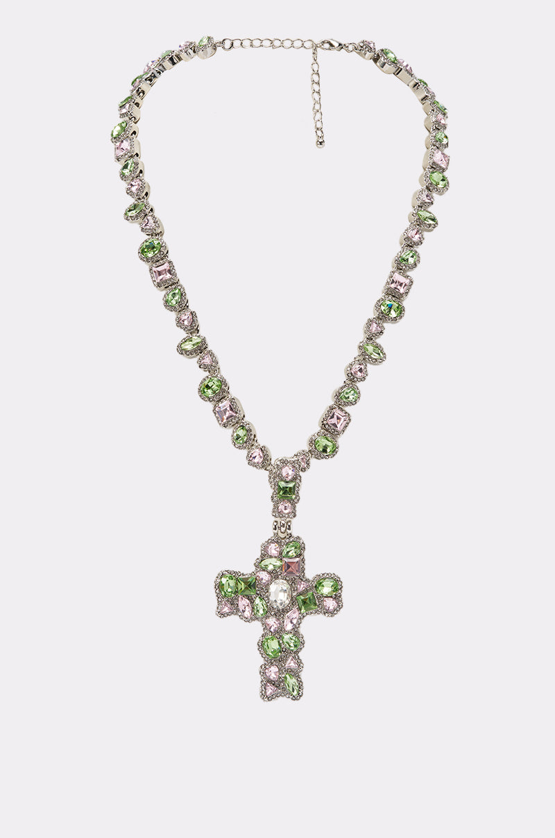 The STAY PROTECTED NECKLACE features green and clear gemstones set in silver with a bold gemstone cross pendant, shown on a plain white background—perfect as festival jewelry. 0