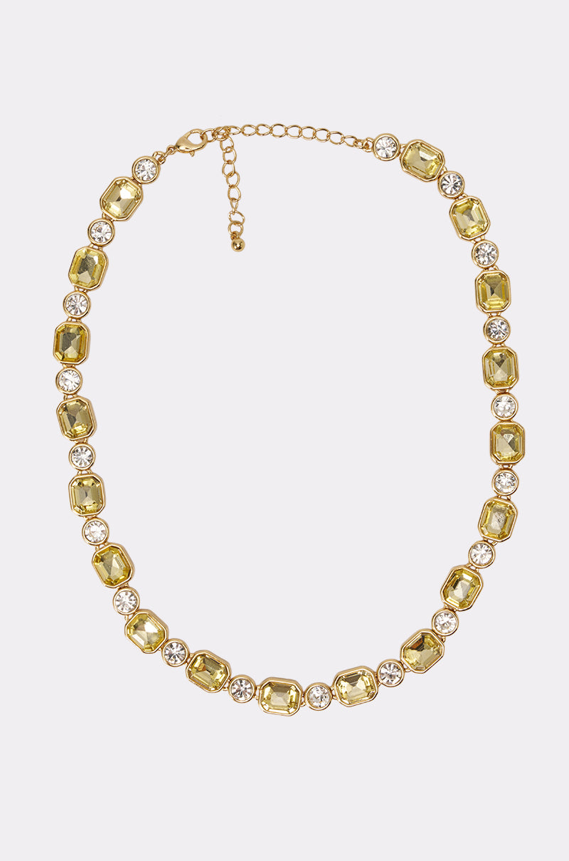 The NIKKI NECKLACE features alternating rectangular yellow rhinestones and round clear stones on a gold-tone chain with an adjustable clasp, adding a radiant touch to any ensemble.