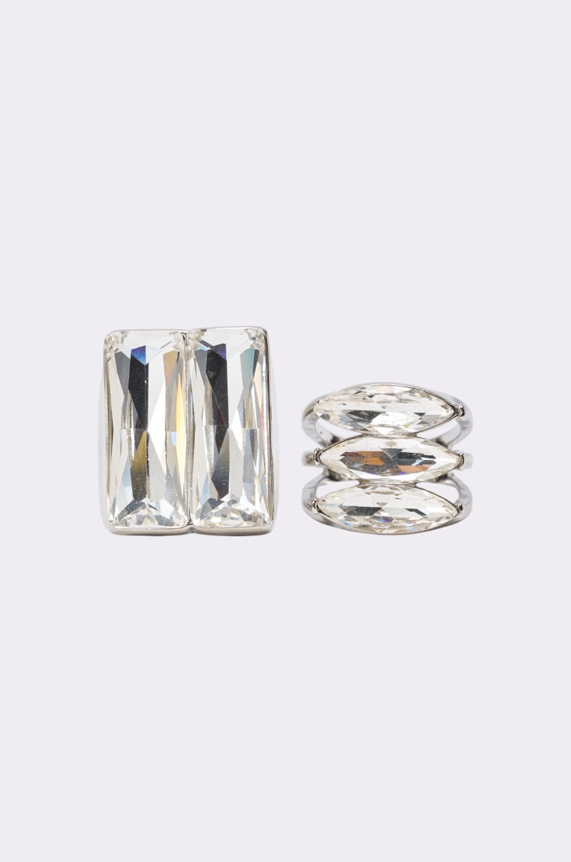 The RIRI RING SET features two silver rings with large, clear rectangular and oval gemstones—a striking statement set for any occasion. Shown side by side on a plain, light background. 1