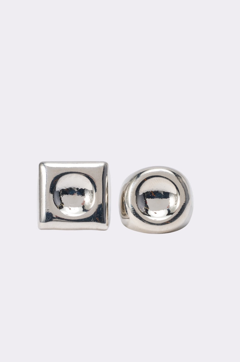 The IM THE INSPO RING SET features two sculptural silver-tone rings: one chunky with a square, domed face, and another with a round, domed center—both shown on a light gray background. 1