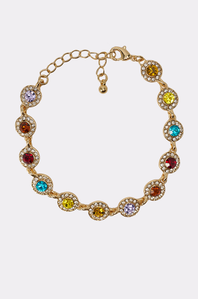 The COME CORRECT NECKLACE is a gold-tone piece adorned with multicolor faceted stones—yellow, red, blue, and violet—each framed by clear crystals. It features an adjustable chain and a lobster clasp. 5