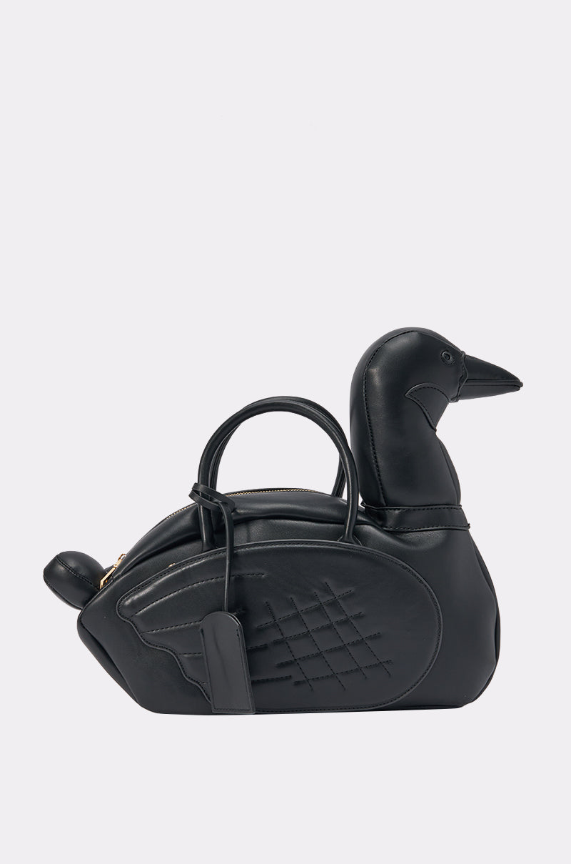 Introducing the DUCK BAG: a black faux leather bag uniquely crafted in the shape of a duck, featuring a rounded body, tail detail at one end, and a sculpted head with beak at the other. Two top handles offer easy carrying, making this playful accessory the ideal streetwear or festival bag for anyone looking to stand out in style.