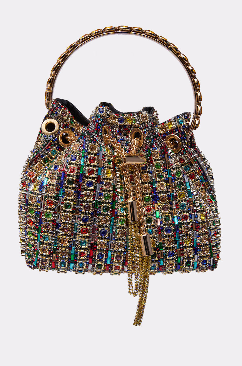 The GEGE BLING PURSE is a small handbag with a gold chain handle, gold hardware, and drawstring closure, featuring a colorful grid of sparkling rhinestones and gems in various shapes and sizes.