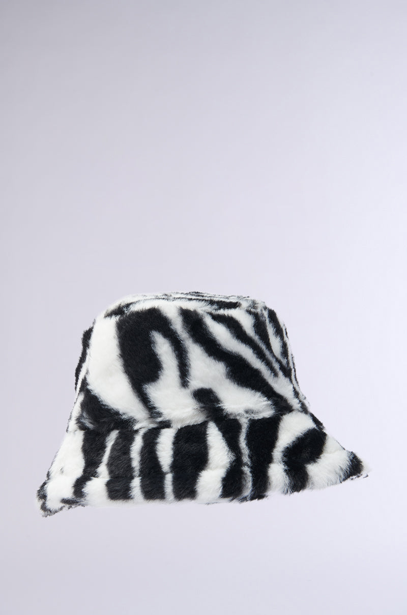 The WILD CHILD ZEBRA FAUX FUR HAT stands out with its black and white zebra pattern against a light gray background, combining style and comfort. This fashionable bucket hat includes adjustable drawstrings for an ideal fit. 3