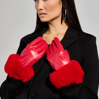 A person wearing a black coat with large red faux fur cuffs and the ALL I WANT IS MONEY FUR GLOVES stands against a plain background. They have long dark hair, are looking to the side, and don stylish large hoop earrings.