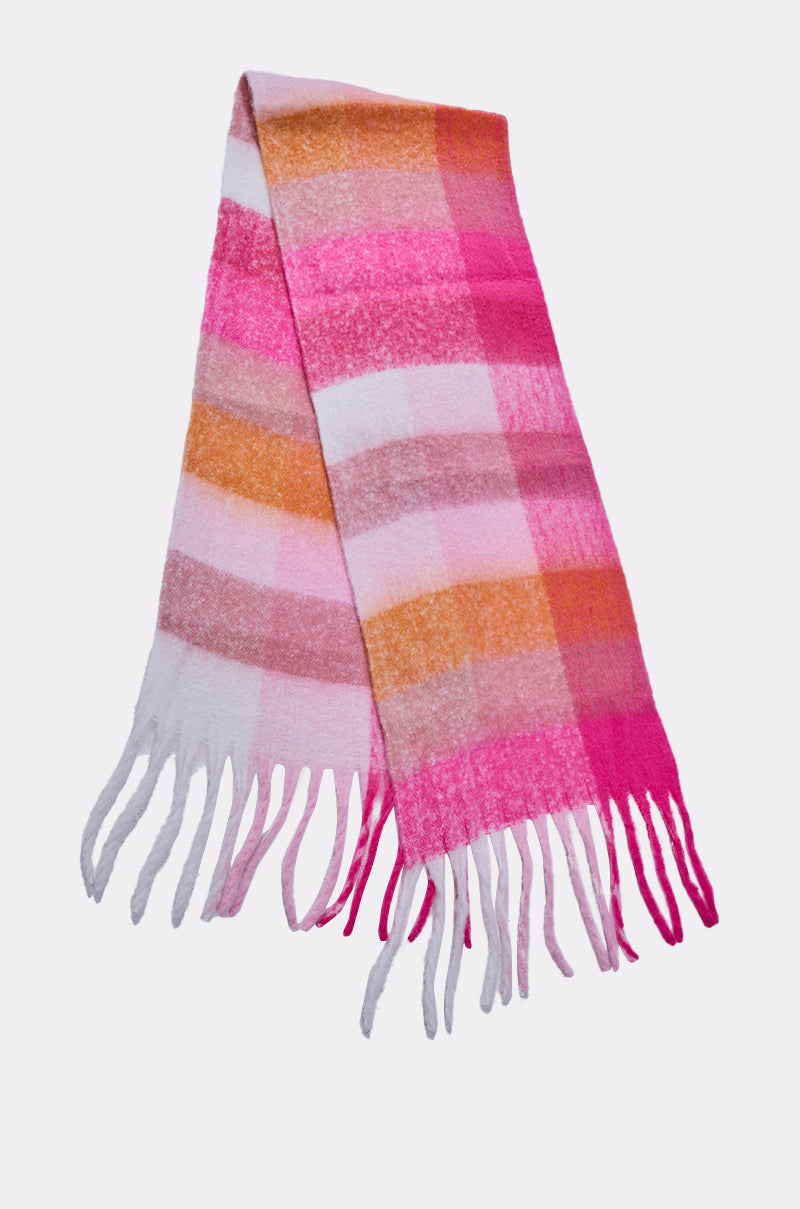 The IN MILAN BLANKET SCARF is a soft, large plaid scarf in pink, orange, and white with fringed ends, shown laid out on a plain white background. 4