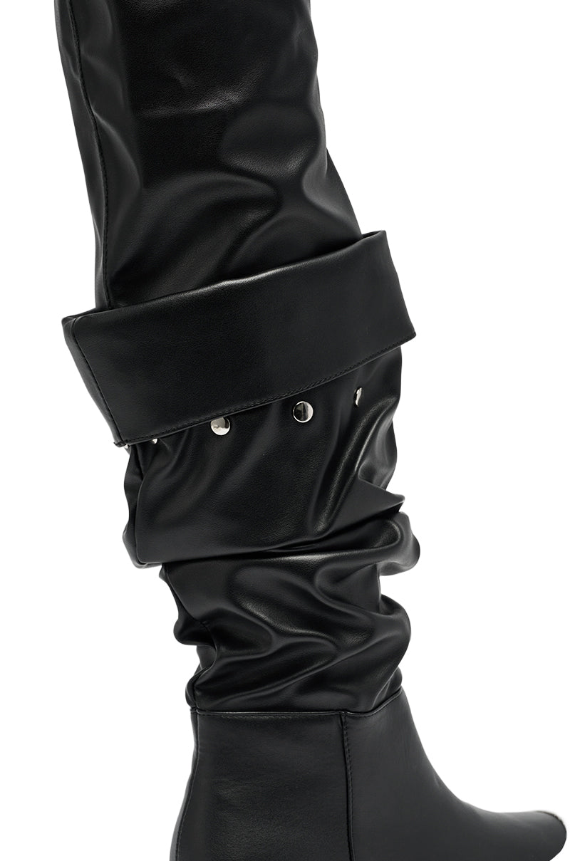 The AZALEA WANG SMARTER BLACK RUCHED PU FLAT BOOT features shiny black ruched material, a wide folded cuff decorated with small silver studs, and a sleek flat sole.