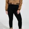 A person is wearing a tan bomber jacket with black trim, paired with SNUGGLE FLEX Fleece Leggings in Black and tan combat boots, standing against a neutral background.