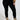 A person wearing the Snuggle Flex Fleece Legging Extended Size in black, paired with a brown jacket and beige lace-up boots, stands against a plain background with hands at their sides, highlighting a casual and stylish ensemble.