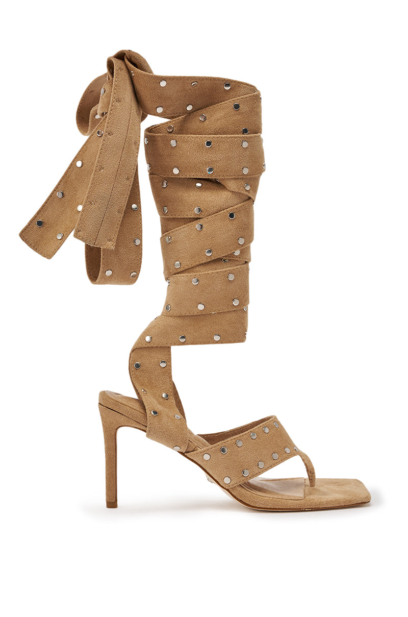 The AZALEA WANG SODALITE NUDE FAUX SUEDE LACE UP SANDAL is a tan high-heeled open-toe sandal featuring silver studs and long, wide lace-up straps that wrap around the calf and tie at the top. 4