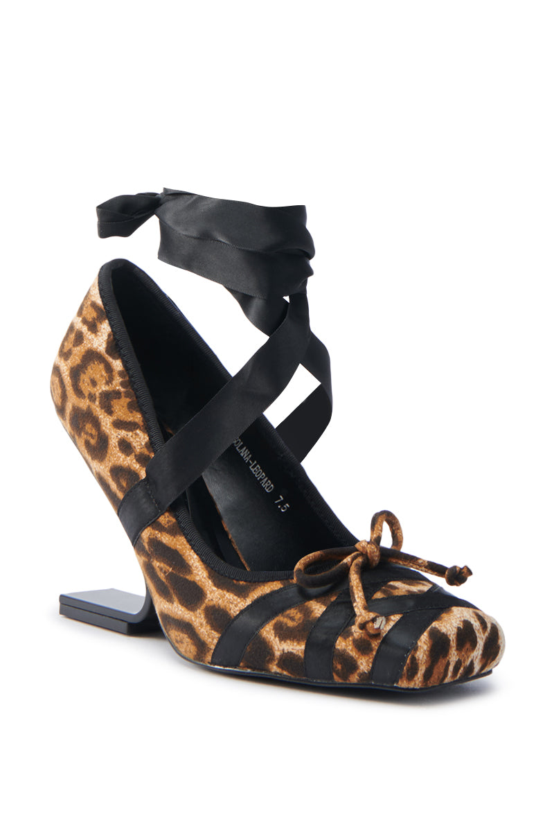 The AZALEA WANG SOLANA LEOPARD WEDGE PUMP has a suede textile upper, unique angled heel, and black ribbon ankle ties. It features a square toe design with a front bow, offering a chic and modern style.