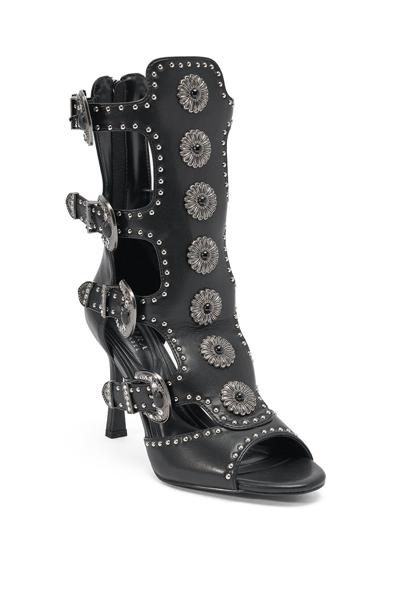 The AKIRA GOLD SOLVEIG BLACK EMBELLISHED WESTERN STILETTO SANDAL is a black sandal with silver studs, multiple western buckles, and large silver floral embellishments up the front. 3