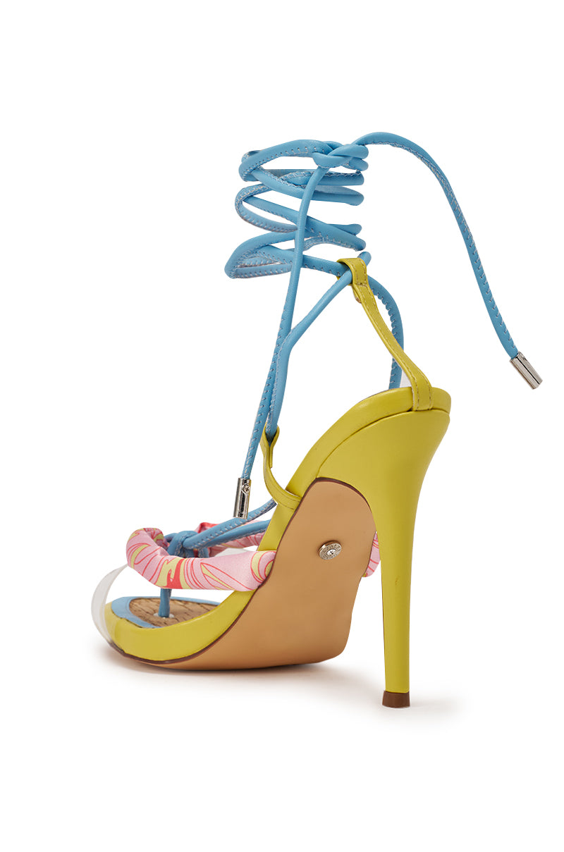 The AZALEA WANG SOMERSET CITRON MULTI STILETTO SANDAL features a yellow heel, blue lace-up straps, pink patterned toe fabric, and a beige sole—colorful summer heels shown from a rear side angle. 4