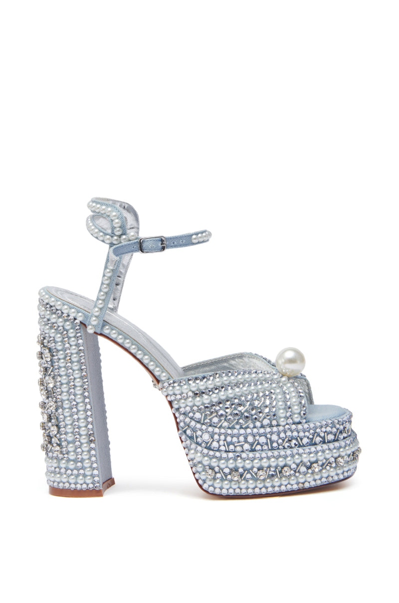The AZALEA WANG SOMETHING BLUE CHUNKY SANDAL is a light blue denim sandal with pearl and rhinestone details, an ankle strap, and a large pearl accent on the toe strap.