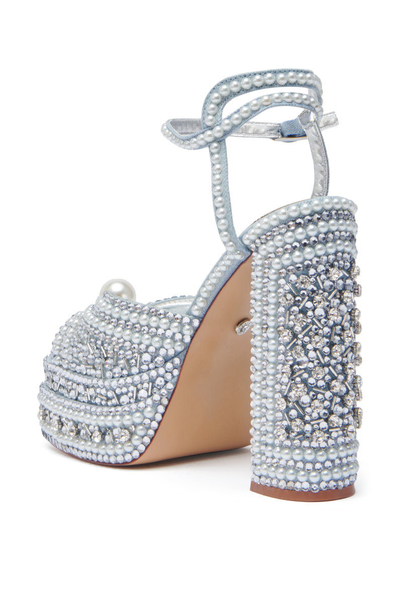 The AZALEA WANG SOMETHING BLUE CHUNKY SANDAL features a thick heel, ankle strap, platform sole, and is adorned with pearl accents and rhinestones for a glamorous sparkle.