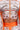 A close-up of a person wearing the CRAZY IN LOVE SATIN ROMPER featuring a colorful baroque scarf print, orange waistband, intricate blue, orange, and white designs, and a visible back zipper that highlights its flowy silhouette.