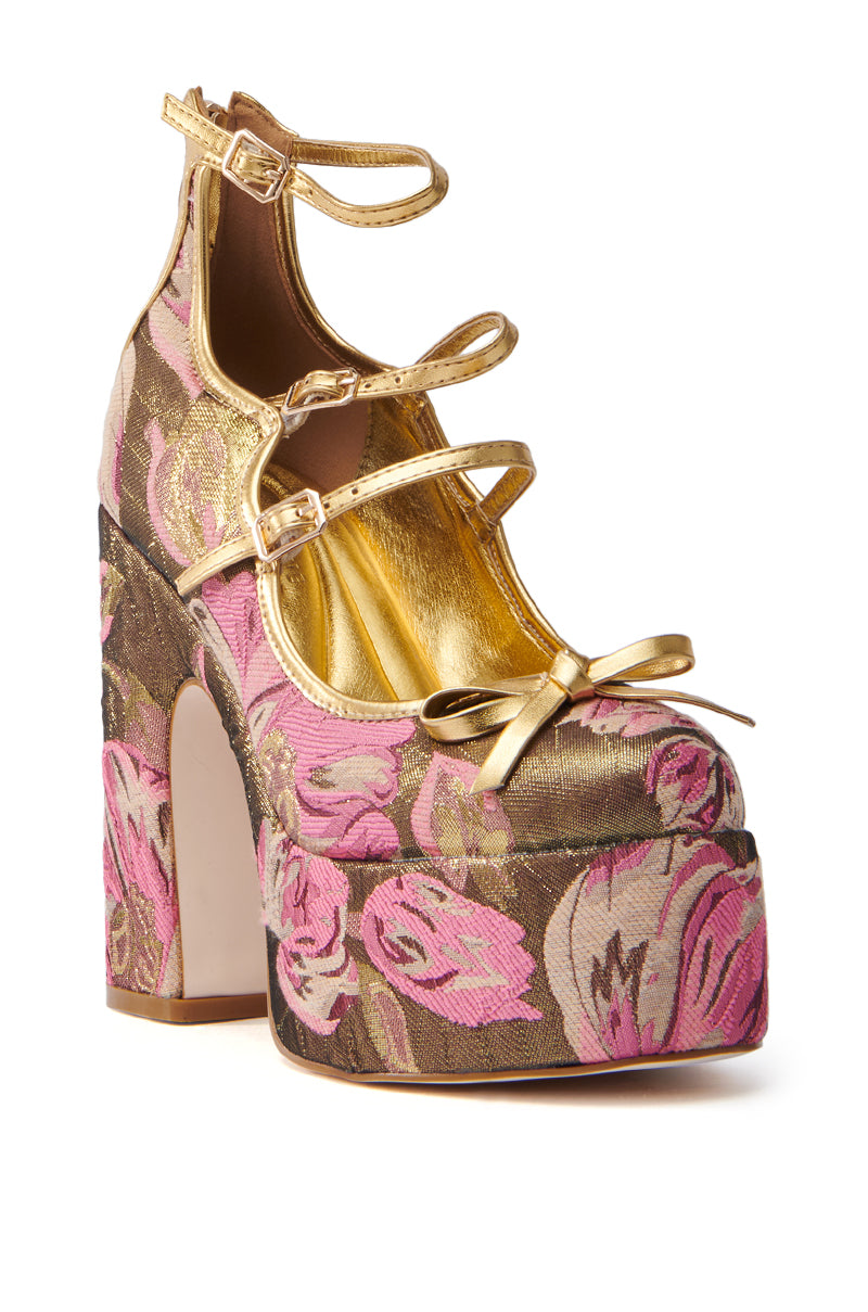 The AZALEA WANG SPROUT GOLD BROCADE PUMP features mega-chunky heels that elevate the platform. Pink and gold floral details adorn the base, while multiple gold straps and a bow grace the front. A metallic gold interior lining adds opulence to this high-heeled shoe.