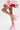 A person poses with one leg bent in a pink and gold floral lace skirt, wearing AZALEA WANG SPROUT PINK CHUNKY PUMP platform heels with ankle straps against a plain white background.